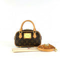 Designer handbag with monogram pattern and gold accents on a white background