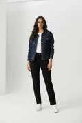 Female model wearing Tommy Jeans navy embroidery denim jacket open over white t-shirt with black pants white sneakers gray studio background