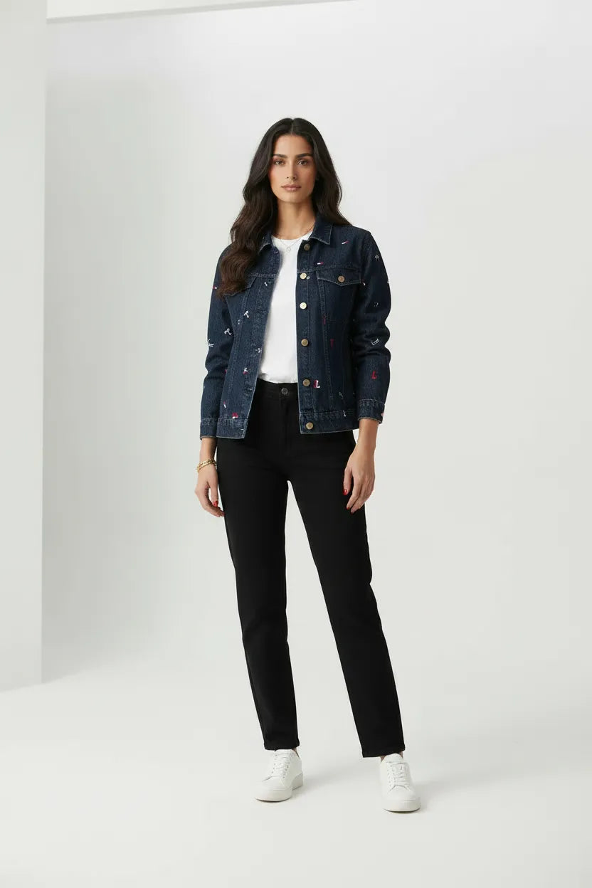 Female model wearing Tommy Jeans navy embroidery denim jacket open over white t-shirt with black pants white sneakers gray studio background