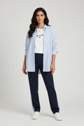 Model wearing a light blue striped shirt and dark pants (the perfect suit),from Tommy. standing in a room.