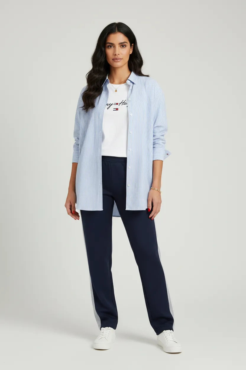 Model wearing a light blue striped shirt and dark pants (the perfect suit),from Tommy. standing in a room.