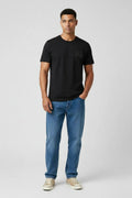 Man wearing a black t-shirt and blue jeans on a white background