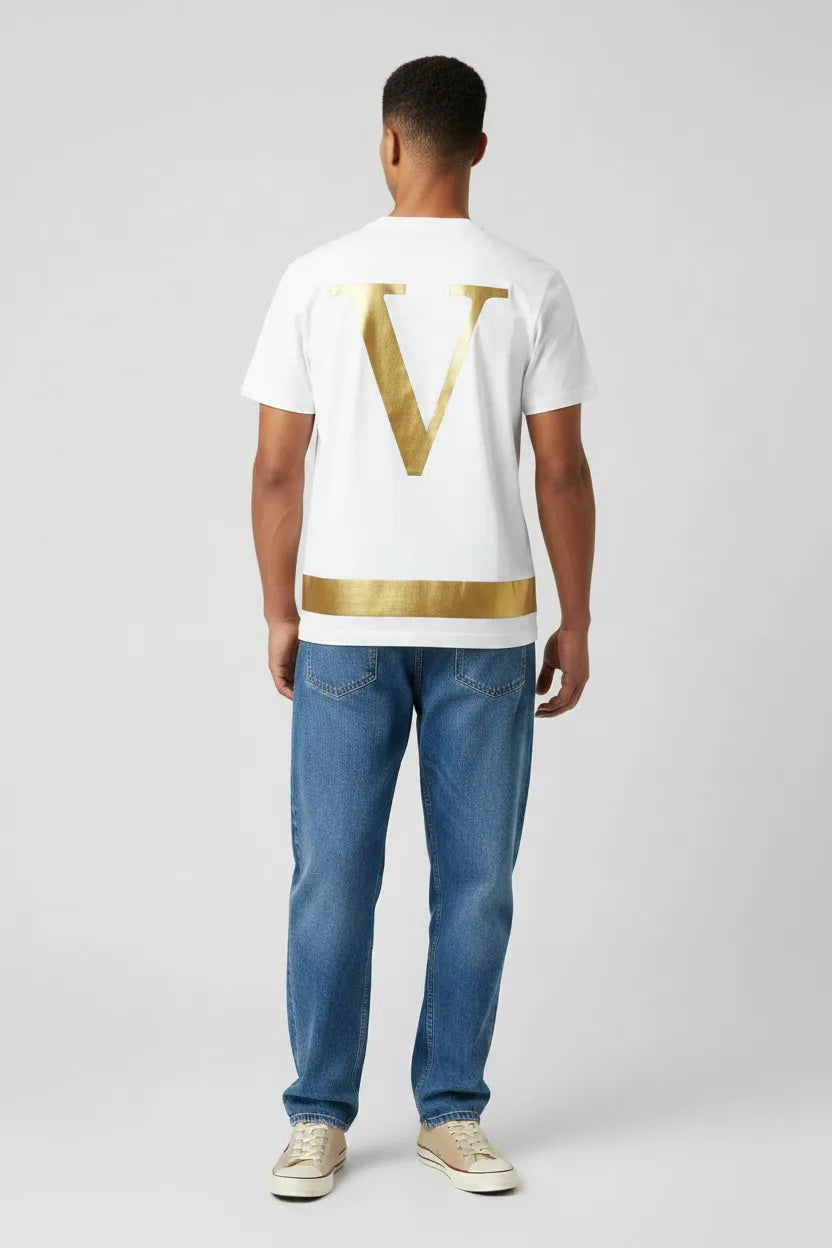 Man wearing a white t-shirt with a gold logo and blue jeans on a light gray background