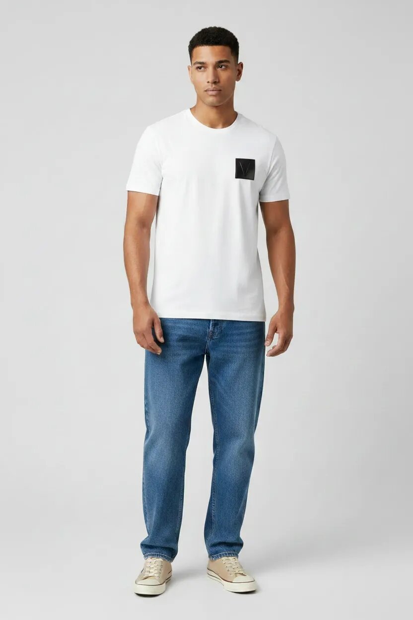 Man wearing a white t-shirt with a black square design and blue jeans on a light gray background